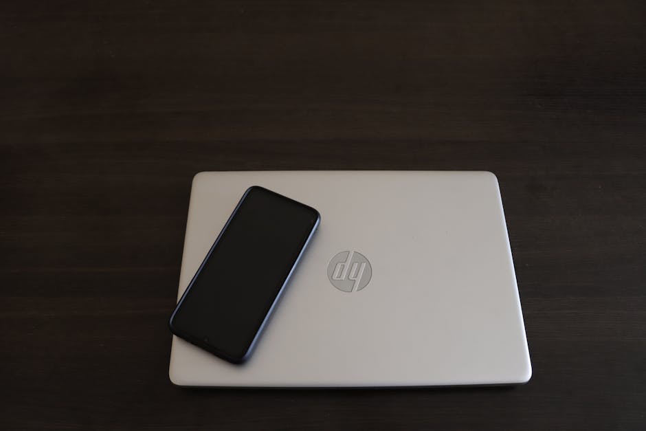 Young person distracted by smartphone while working at a laptop