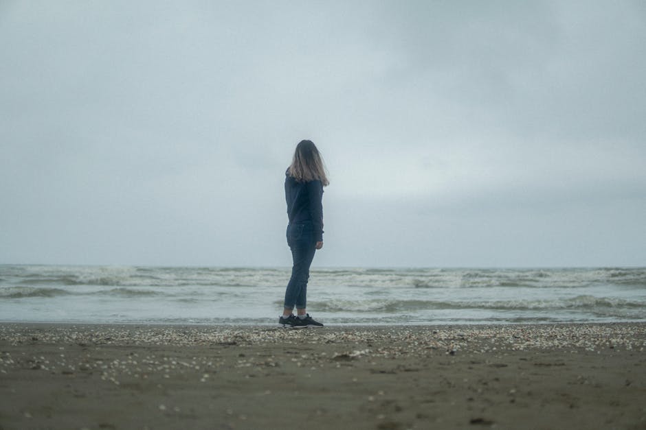 Person standing on a beach looking at the ocean horizon