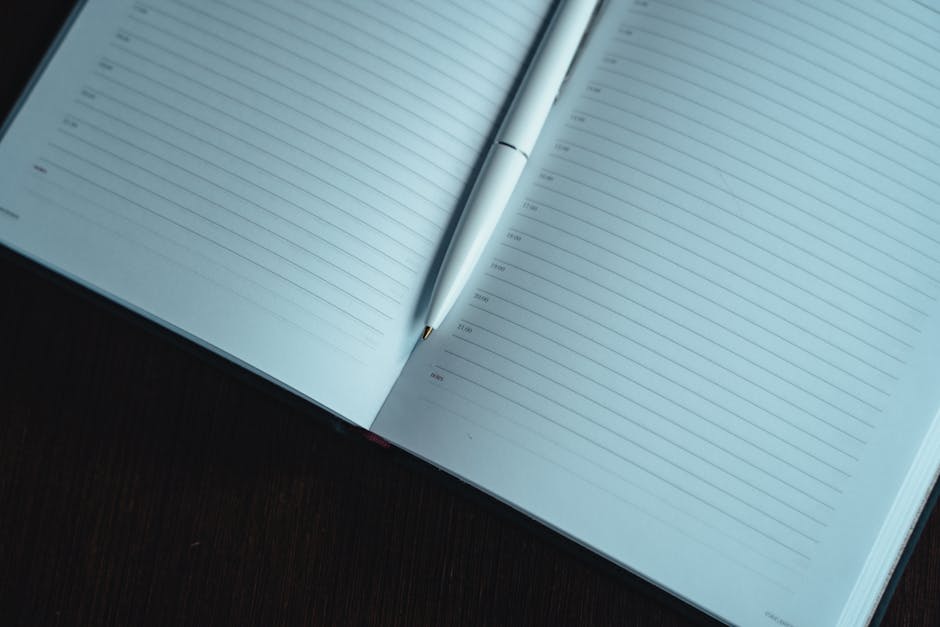 Person hesitating before starting a task with notebook and pen on a desk