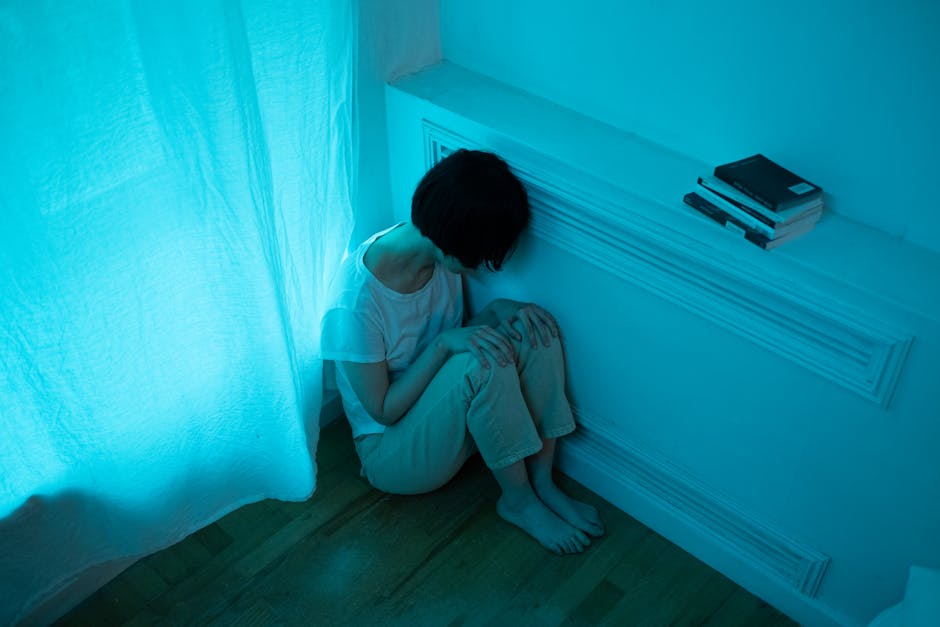 Person sitting alone in a dim room, reflecting sadness and emotional distress