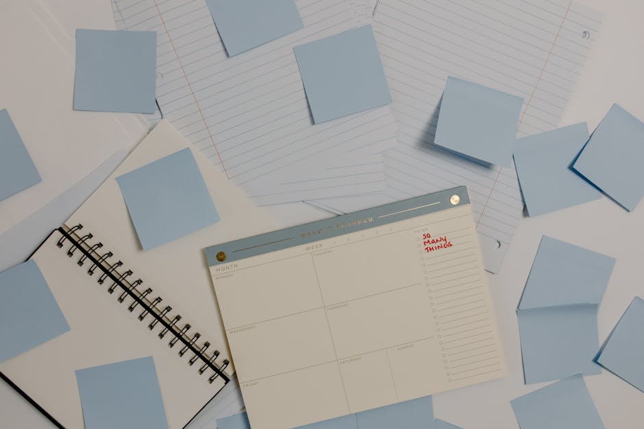 Messy desk with sticky notes, calendar and laptop representing time management and priorities