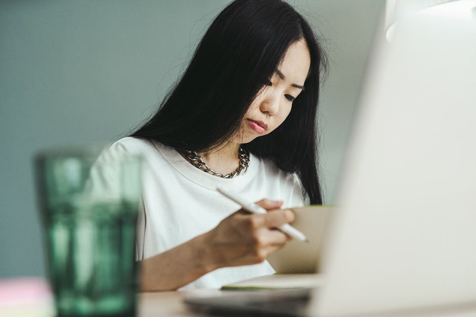 Quiet workspace with focused person writing or working on a laptop