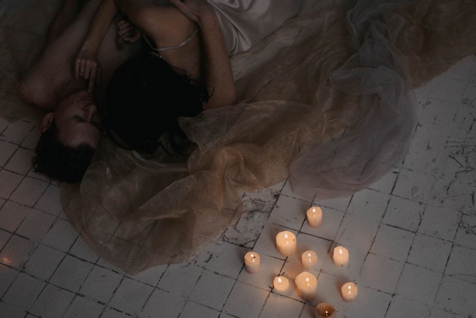 Couple in a warm intimate setting with candles and soft lighting exploring sensuality