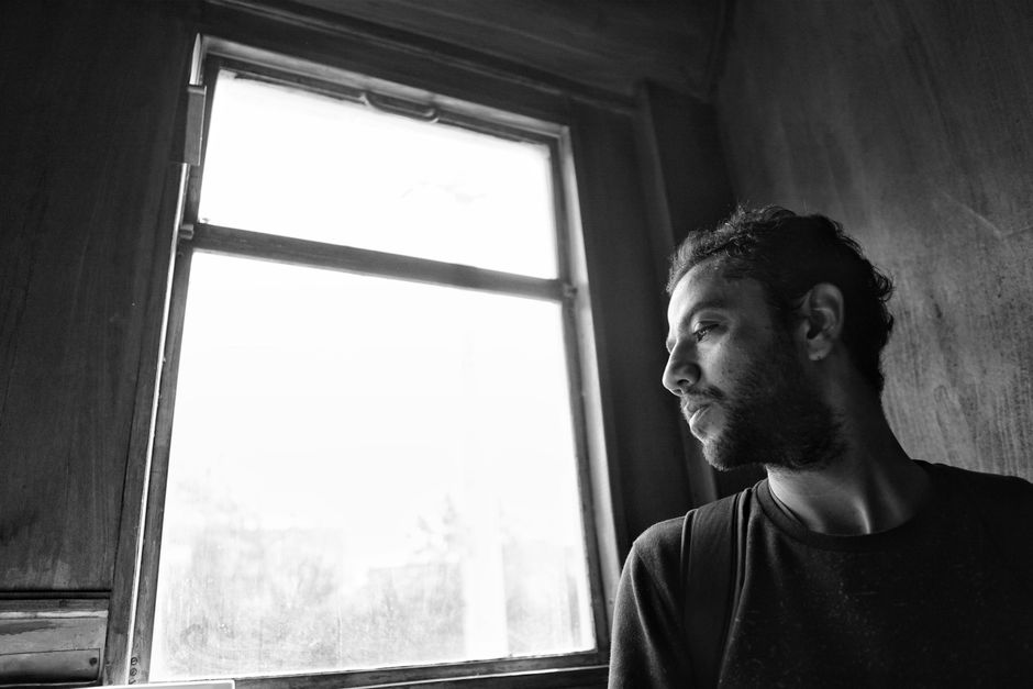 Person sitting alone by a window, reflecting with a negative mindset
