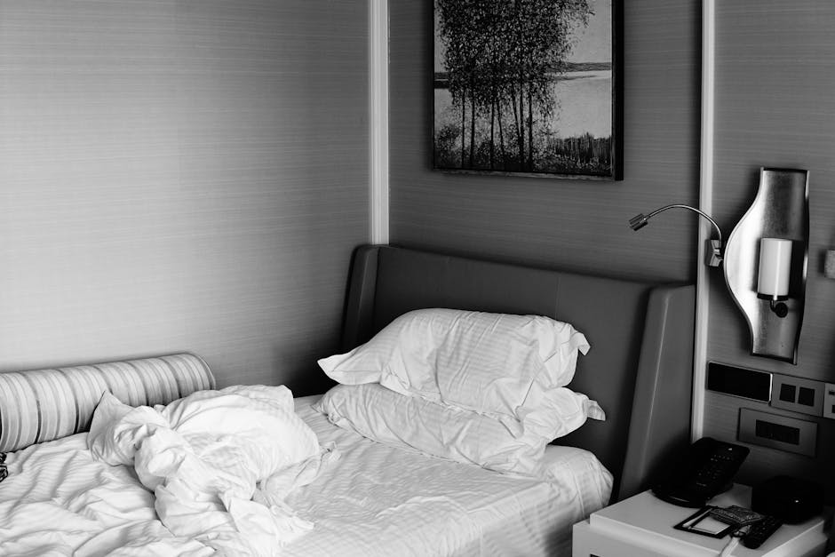 Messy bedroom with unmade bed and phone on the sheets
