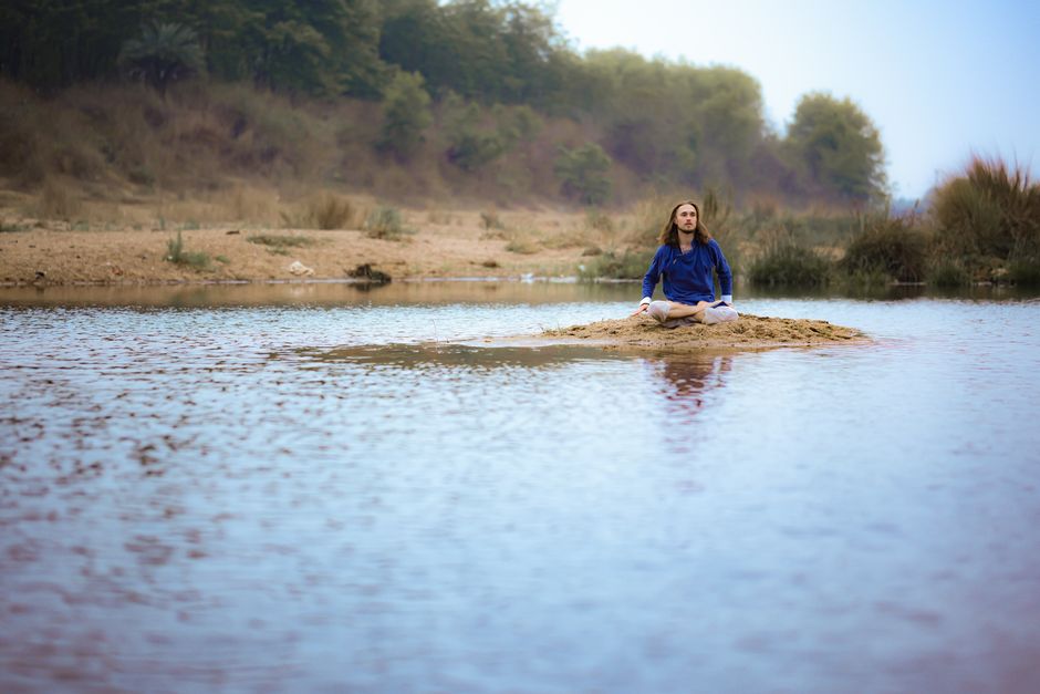 Person meditating in a calm natural setting, representing mindfulness and ego reduction