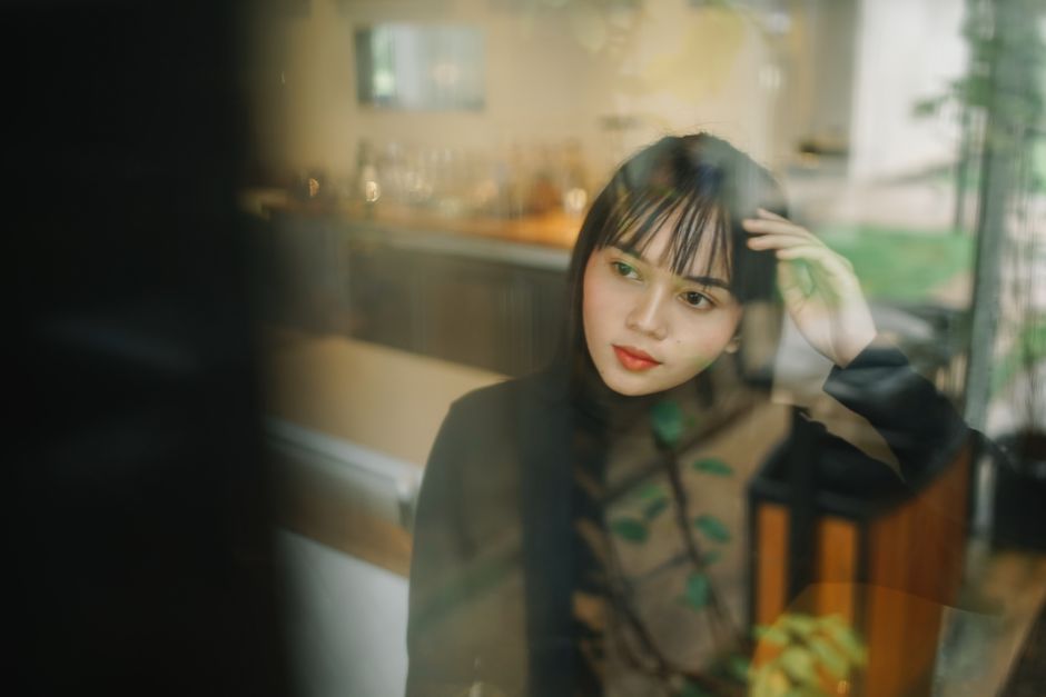Woman looking thoughtful by a window, reflecting on relationships and emotional distance