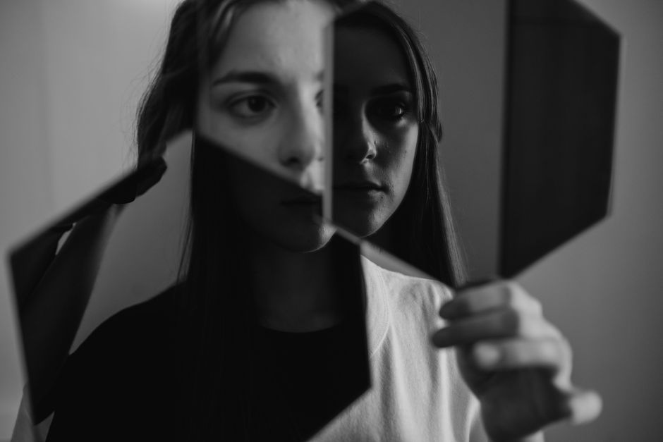Personne regardant son reflet dans un miroir avec une expression réfléchie