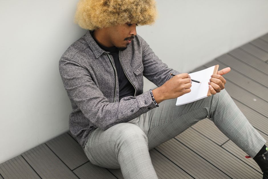 Person reflecting alone with a notebook, thinking about assumptions and thoughts