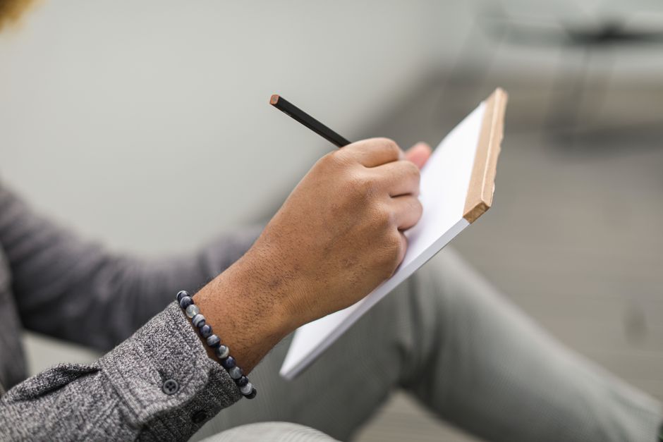 Person looking stressed while writing thoughts in a notebook
