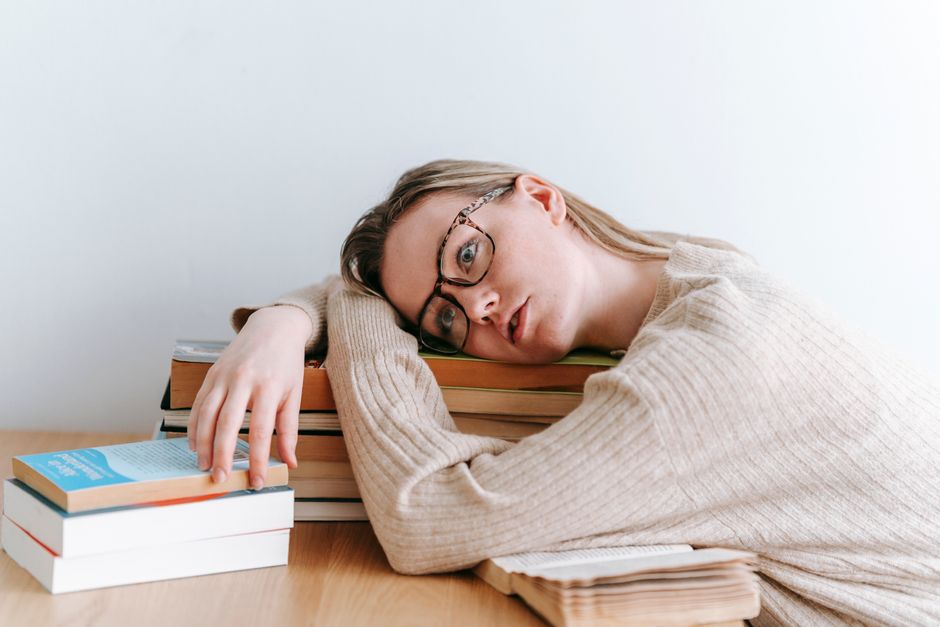 Overwhelmed student studying at desk with books