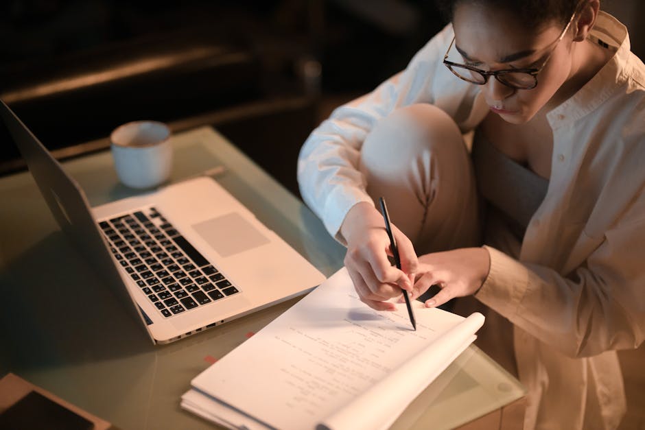 Person working alone at night with laptop and notes