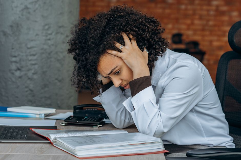 Stressed professional working late at a desk with laptop and papers