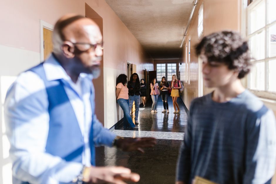 Jeune personne assise seule dans une salle de classe ou un couloir, ambiance de soutien et vulnérabilité