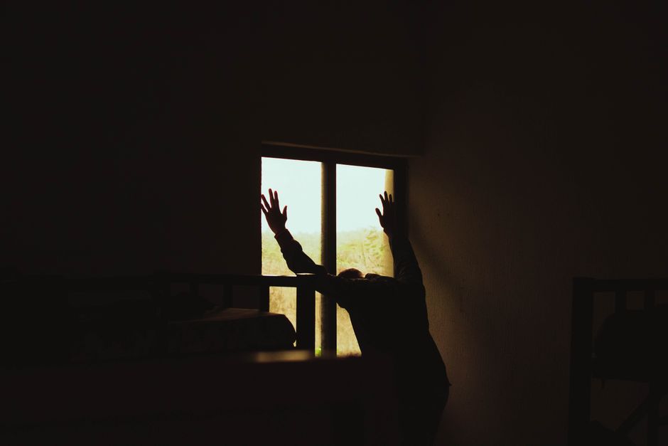 Silhouette d'une personne seule dans une pièce sombre, évoquant la détresse et l'isolement