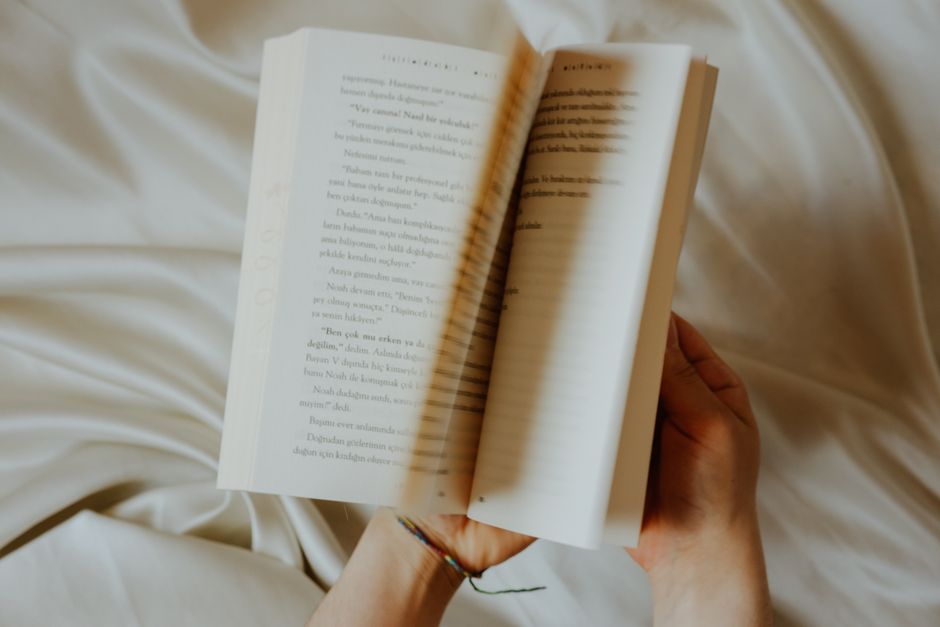 Person reading a book with a blurred romantic cover concept