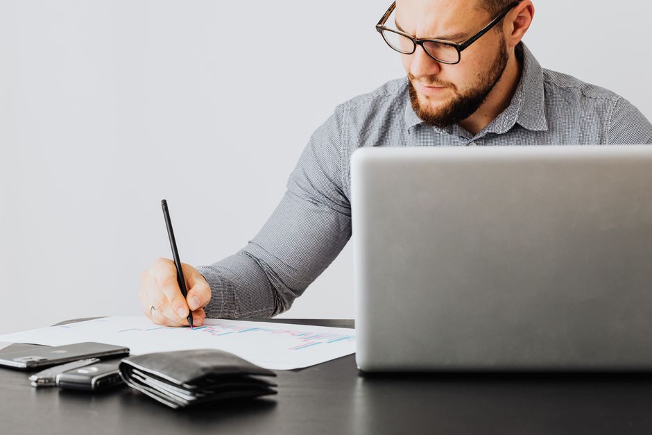 A young professional looking uncertain at a desk with documents and laptop