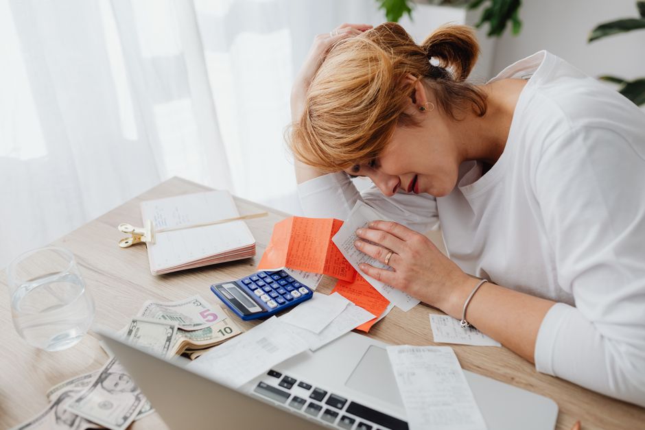 Stressed person reviewing bills and bank statements at home