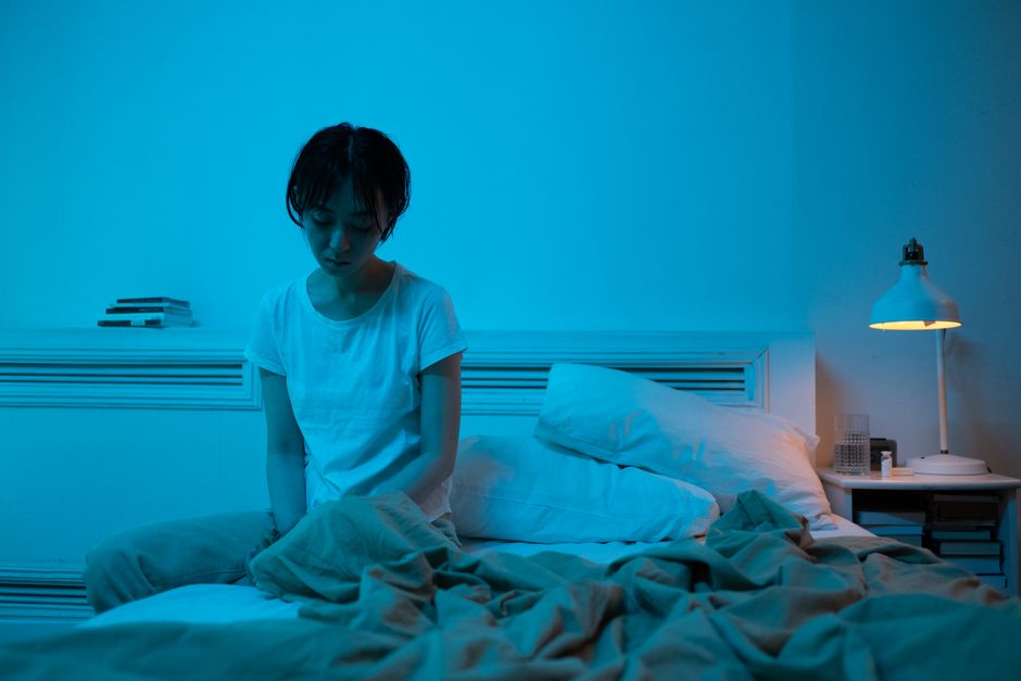 Person sitting alone on a bed in a dim room