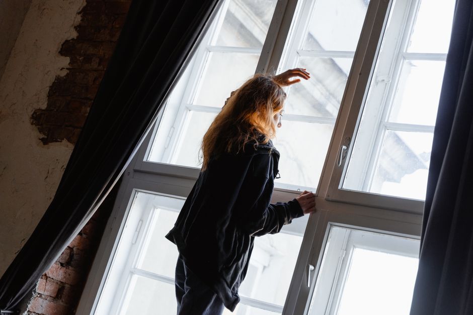 Personne assise seule près d'une fenêtre après une rupture amoureuse