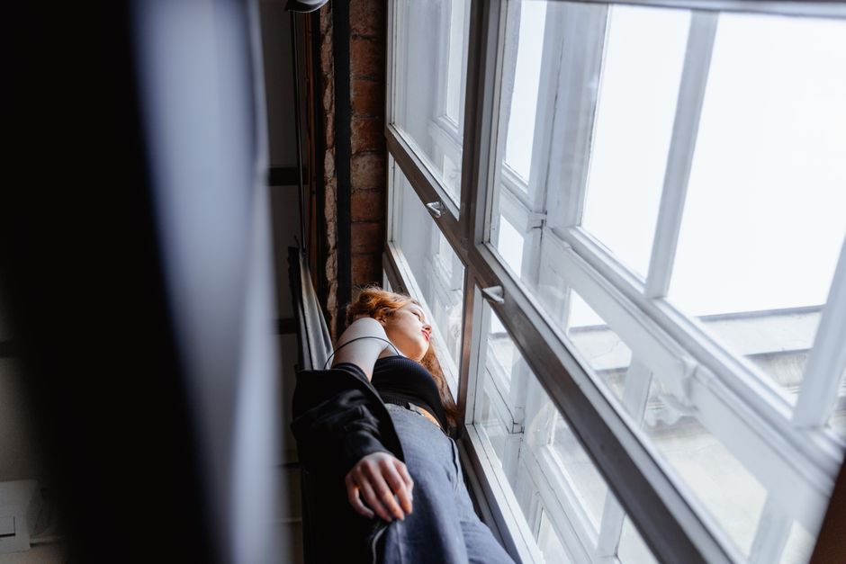 Person sitting alone by a window, reflecting on a difficult relationship