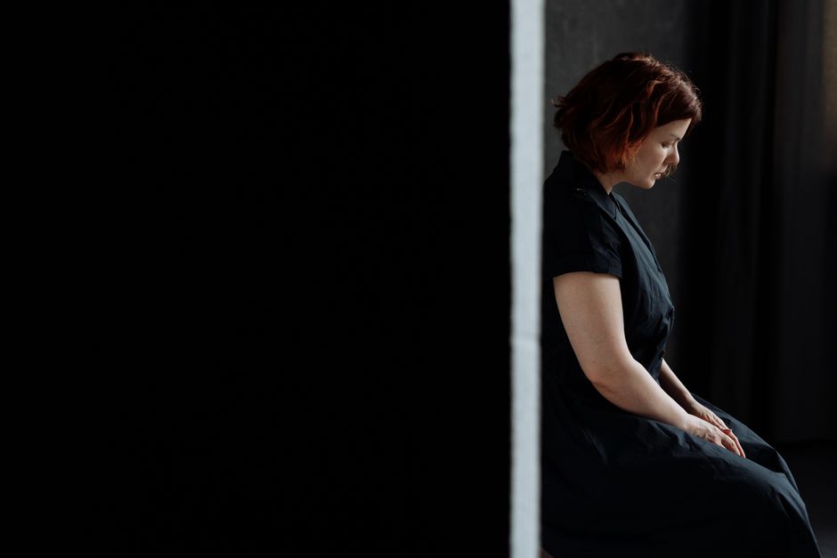 Person sitting alone in a quiet room, overwhelmed and reflective