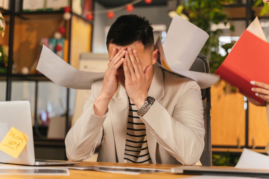 Stressed professional reviewing documents at a desk late at night