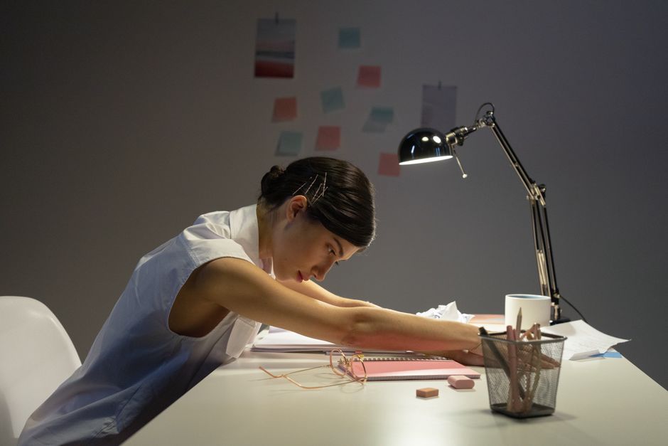 Personne travaillant tard le soir dans une ambiance sombre et épuisée